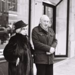 Ils attendaient le passage au vert pour traverser. Ils se parlaient comme se parlent les vieux couples qui ne s’aiment plus, qui ne se sont peut-être jamais aimé. Un mariage de convention, dans une bourgeoisie genevois qui ne veut pas diluer son sang et sa fortune. Un mariage malheureux, mais qui dure, parce qu’on ne divorce pas, ça ne se fait pas.
Ils étaient là, tous les deux. J’ai appuyé sur le bouton, et il m’a vu. Il m’a apostrophé, comme on parle à un inférieur, à un larbin, pour m’interdire de les photographier. Je lui ai dit, sur un ton tout aussi désagéable, que je photographiais la devanture au dessus d’eux. Cette explication, et l’aplomb avec lequel je l’ai proférée, les a plongés dans un abîme de perplexité.
Le bonhomme est passé au vert, j’ai traversé la rue et continué mon chemin.